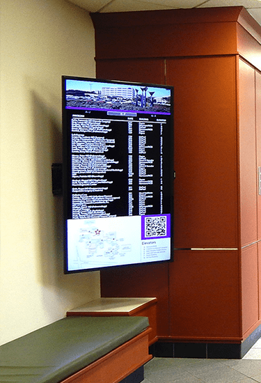 A TV on a wall with digital signage displaying live data