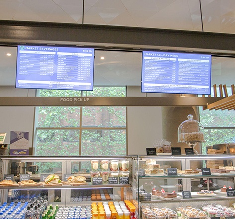 Two digital signage TV's displaying a food menu in a bakery shop