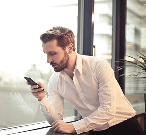 Image of business individual holding a phone by a window