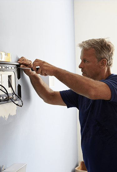 Image of a person installing TV at the wall