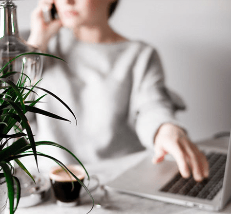 Woman on a phone call about digital signage as she uses a laptop